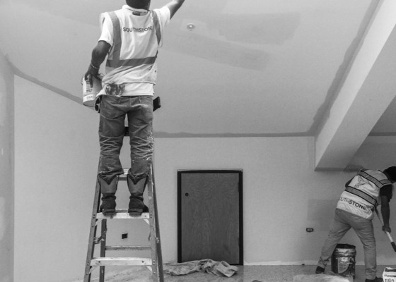 Commercial painter on a ladder painting a ceiling