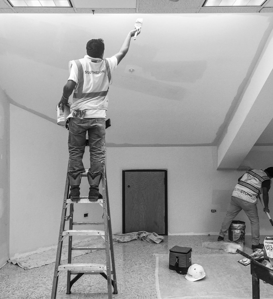 Commercial painter on a ladder painting a ceiling